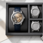Collector examining several high-end mechanical watches beside reference notes