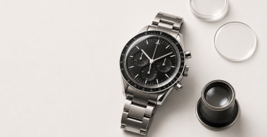 Steel chronograph watch beside a loupe and blank reference card for a buying guide